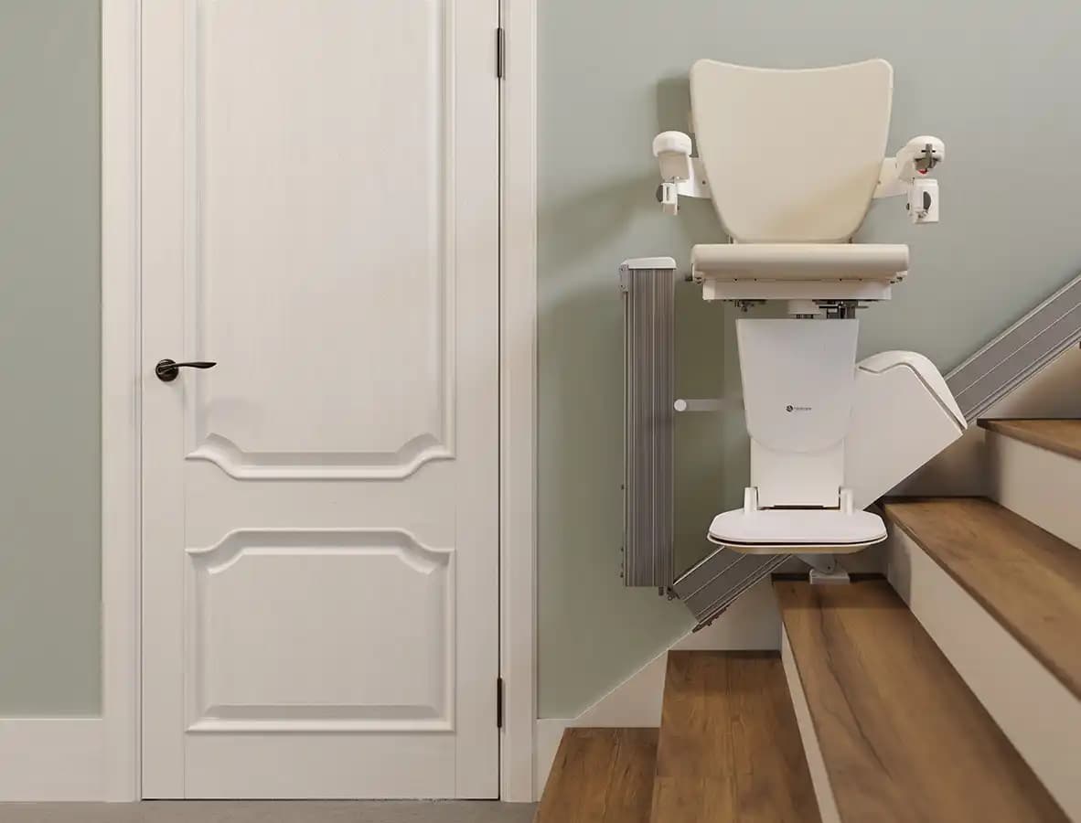 Savaria Handicare 1100 straight stairlift with Style Seat, folded seat and armrests, slim 12.6-inch profile, covered rail near doorway on wood stairs