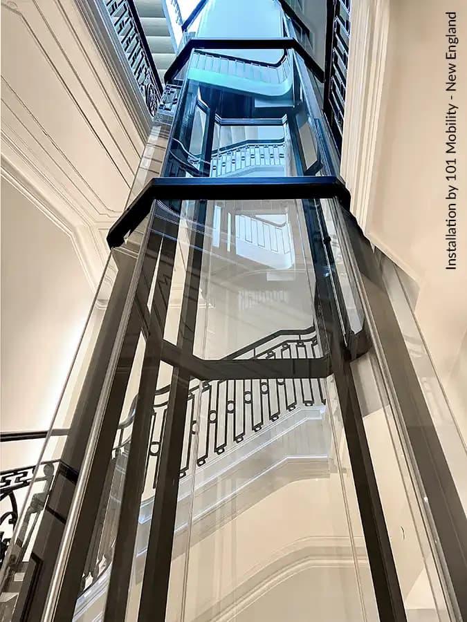Savaria Vuelift octagonal residential elevator with black steel frame and glass shaft in multi-story luxury home stairwell with skylight