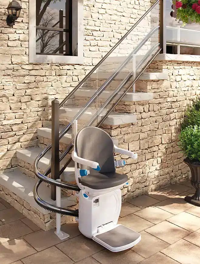 Savaria Handicare 4000 outdoor twin-rail curved stairlift with weather-resistant Outdoor Seat in slate grey upholstery, UV protection, and twin-rail system on exterior brick stairway